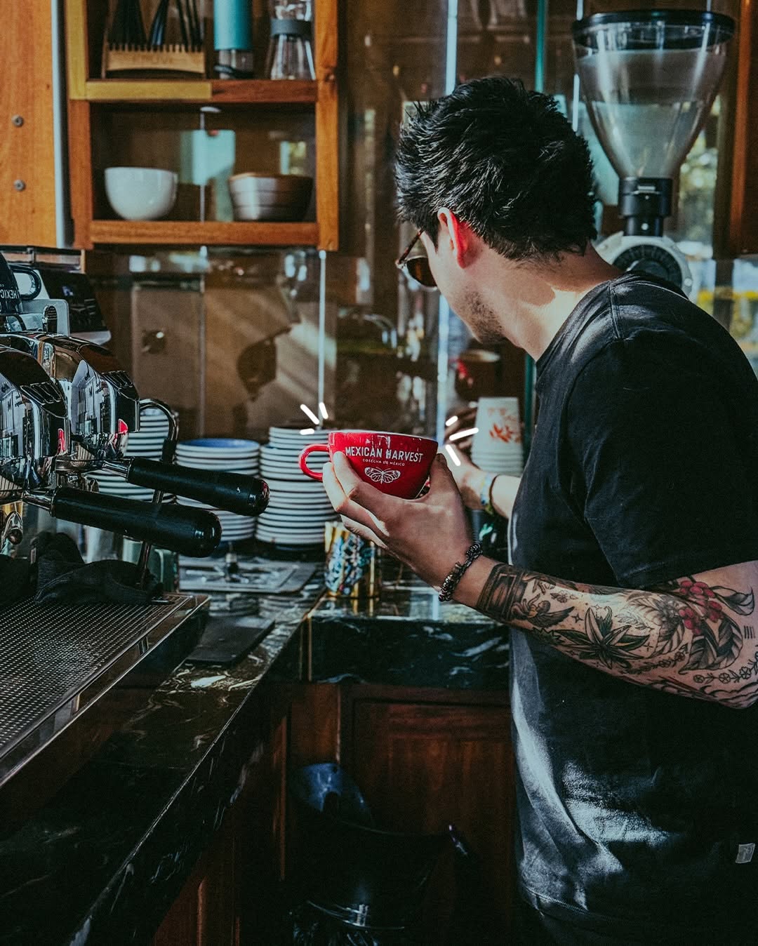 Barista con la taza roja de Mexican Harvest en la barra de espresso