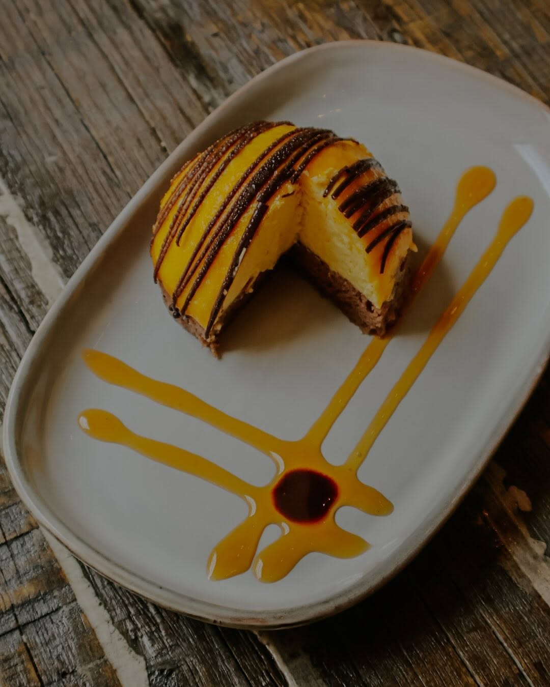 Cheesecake de mango con coulis servido en plato artesanal