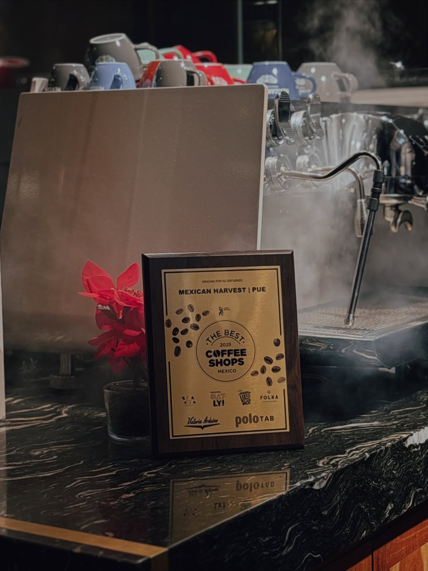 Placa del premio The Best Coffee Shops México 2025 junto a la máquina de espresso